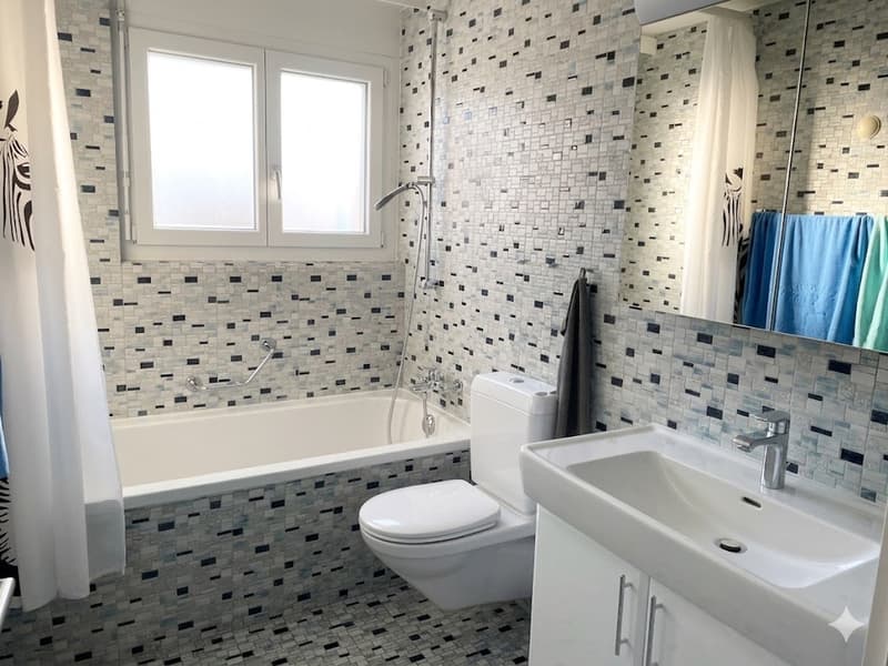 Bathroom with bathtub, toilet, sink, and mirror, tiled walls and floor, shower head, and towel rack.