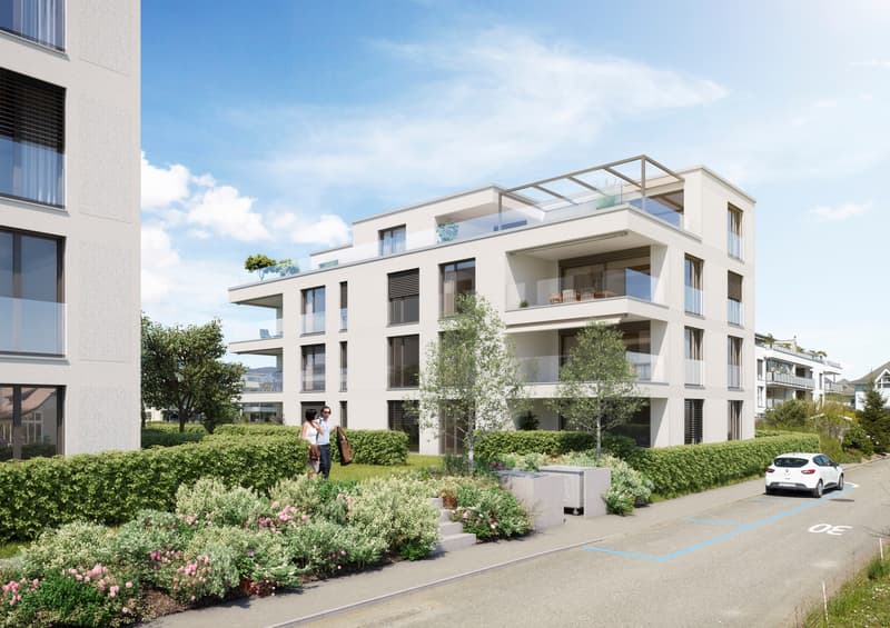 Modern multi-story apartment building with balconies, surrounded by landscaped gardens and parking spaces
