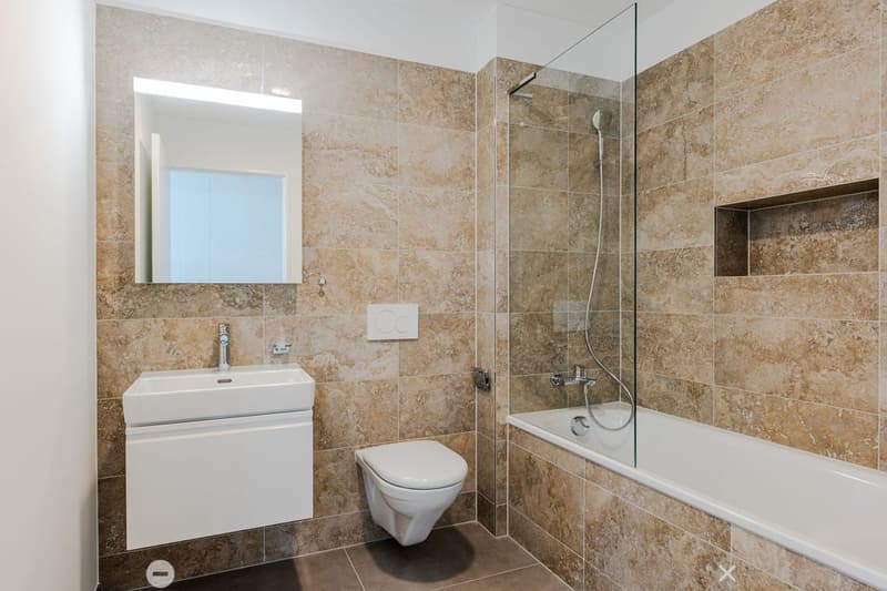 modern bathroom, beige tiles, white vanity, glass shower, bathtub, toilet, wall-mounted mirror