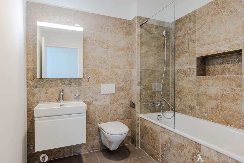 modern bathroom, beige tiles, white vanity, glass shower, bathtub, toilet, wall-mounted mirror