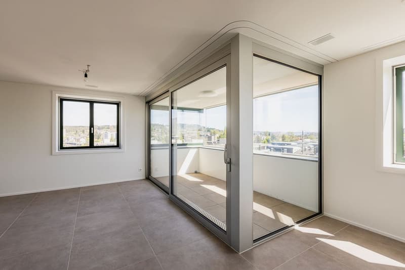 empty room with sliding doors opening to balcony, tiled floor, large windows, city view