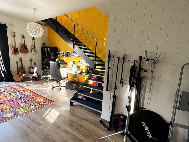 Room with guitars on wall, staircase, desk, guitar accessories, floor, colorful rug
