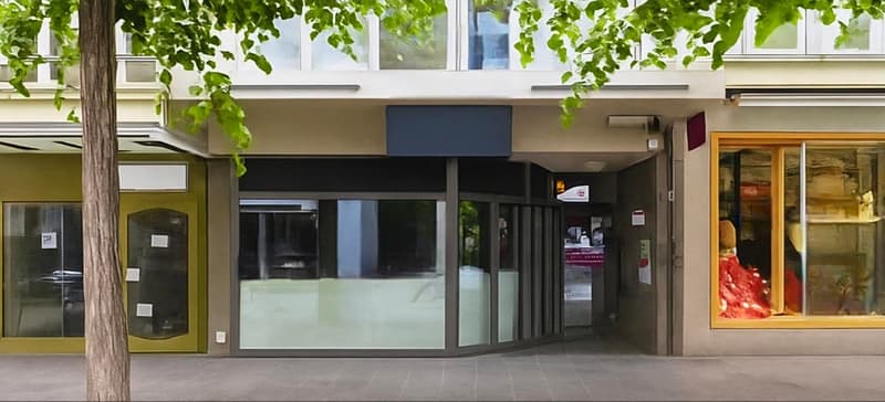 Corner building with glass doors and windows, open entrance with revolving door, two shops with glass windows and doors.