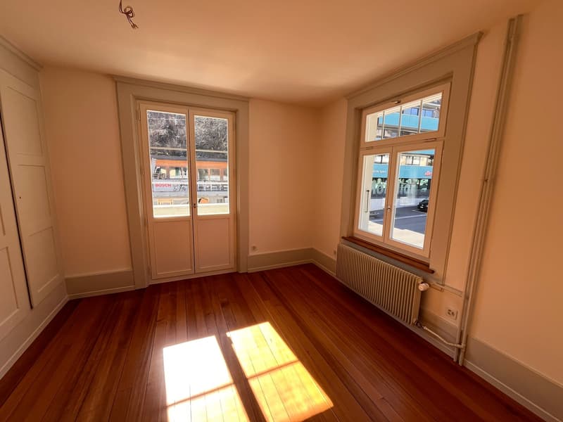 empty room, wooden floor, white walls, two doors, two windows, radiator, sunlight