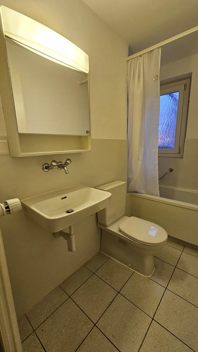 Bathroom with sink, toilet, bathtub, shower curtain, mirror, and light above mirror