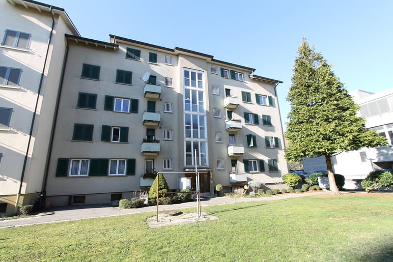 6 story apartment building, multiple balconies, well kept garden, outdoor seating, grass