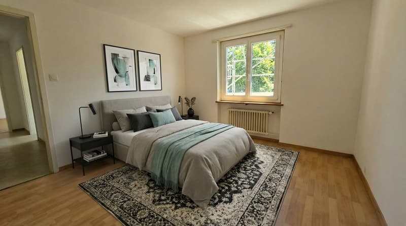 Bedroom with wooden floor, two framed art pieces, double bed, nightstands, lamps, rug, and window with a view of trees.