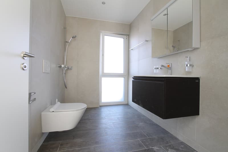 modern bathroom with white toilet, shower, sink, mirror, and tiled floor