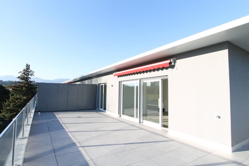 modern building with a balcony, red awning, glass doors, and a garage