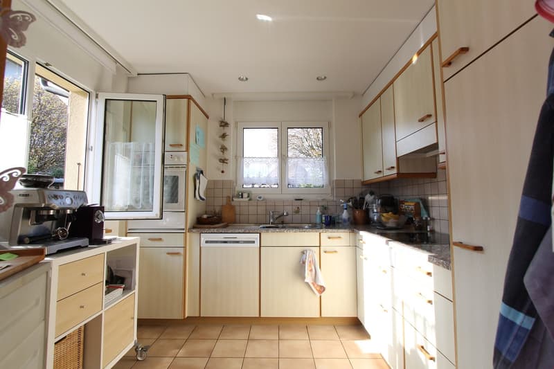 modern kitchen with wooden cabinets, tiled floor, dishwasher, coffee machine, sink, windows