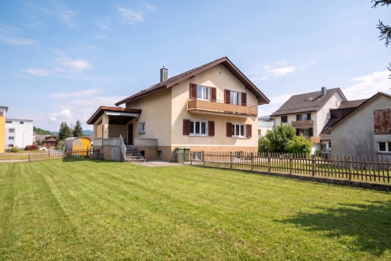 3 story house, beige exterior, brown roof, balcony, large front yard, wooden fence