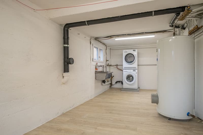 A small room with a washing machine, a sink, and a water heater.