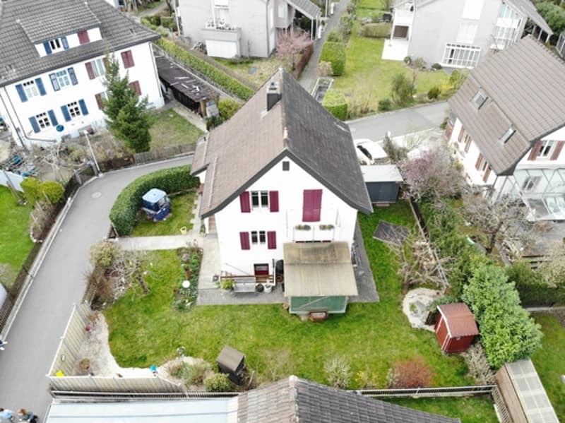 Single family house, white exterior, red shutters, brown roof, driveway, garden, shed, neighboring houses