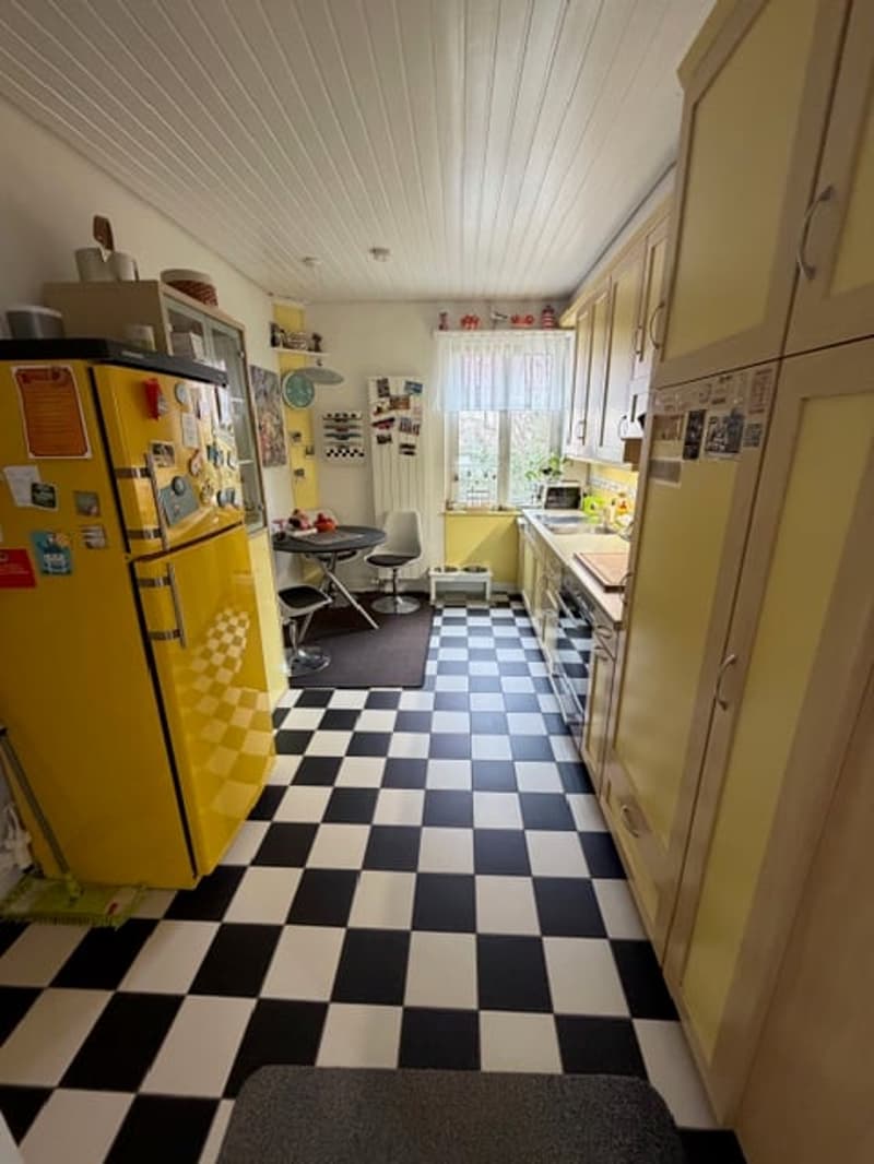 kitchen with yellow fridge, black and white checkered floor, yellow cabinets, dining table, chairs