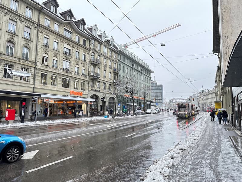urban street scene, multiple buildings, tram lines, people walking, car, snow on the ground