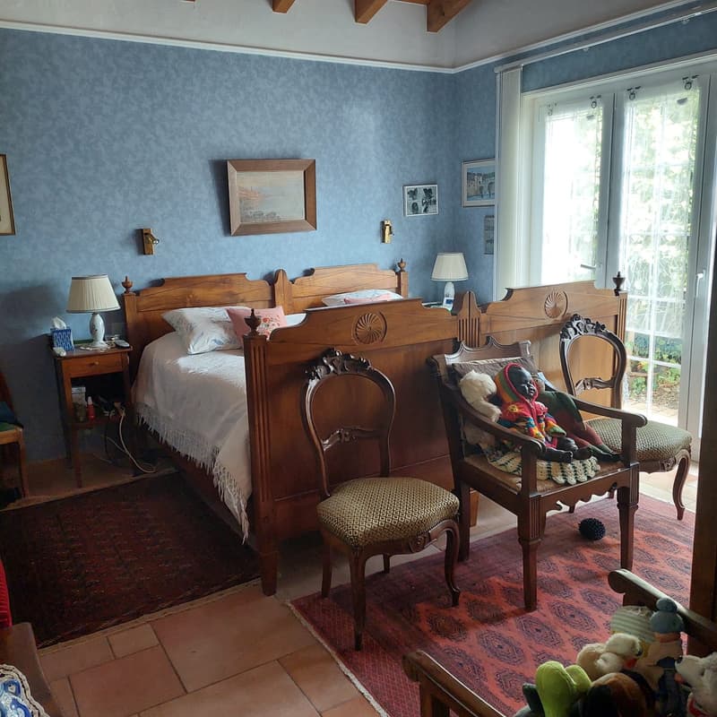 Blue walls, wooden bed, 2 night stands, 2 chairs, toys, lamps, framed pictures, large windows