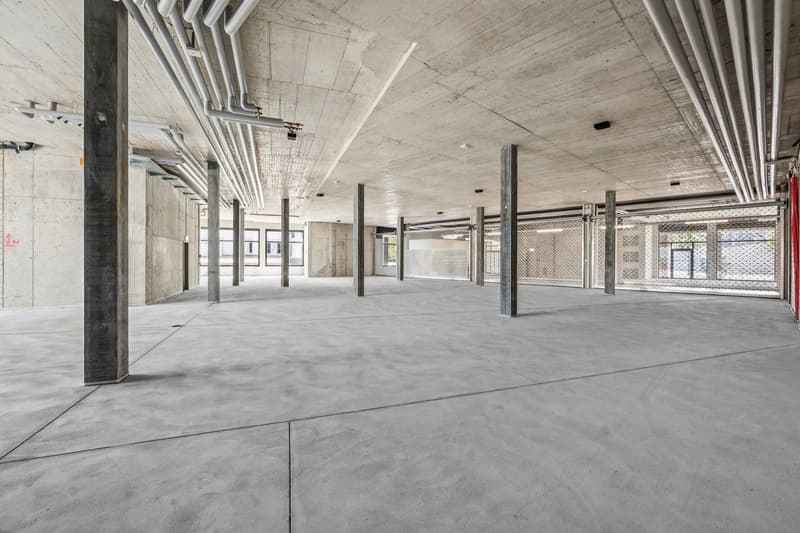 Large open floor plan with concrete floors, exposed ceiling, and metal support columns. The space appears to be an unfinished commercial or industrial building, ready for tenant improvements or renovations.