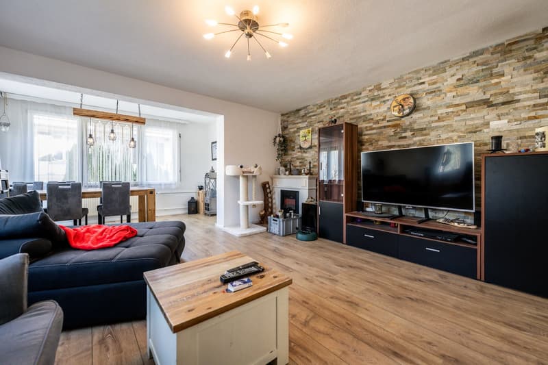 wooden floor, brick wall, large windows, sofa, tv, fireplace, dining table, chair