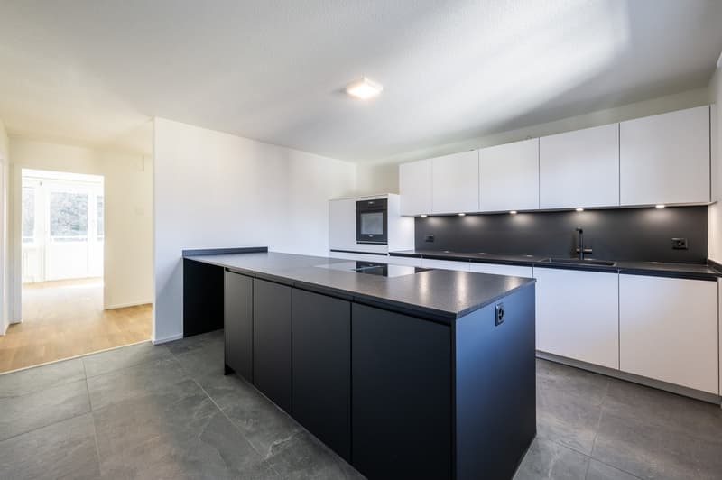 modern kitchen with black countertops, white cabinets, built-in oven, sink, and faucet