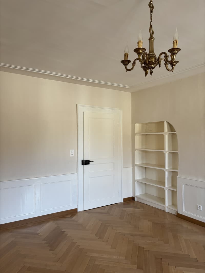 white walls, wooden herringbone flooring, white door, built-in arched shelf, chandelier