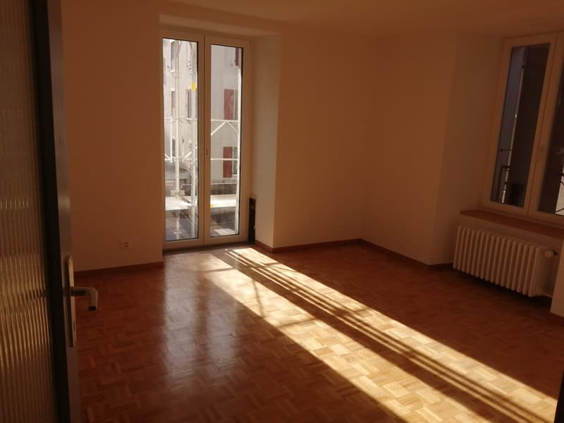 Empty room, wooden floor, sliding glass doors to balcony, heater