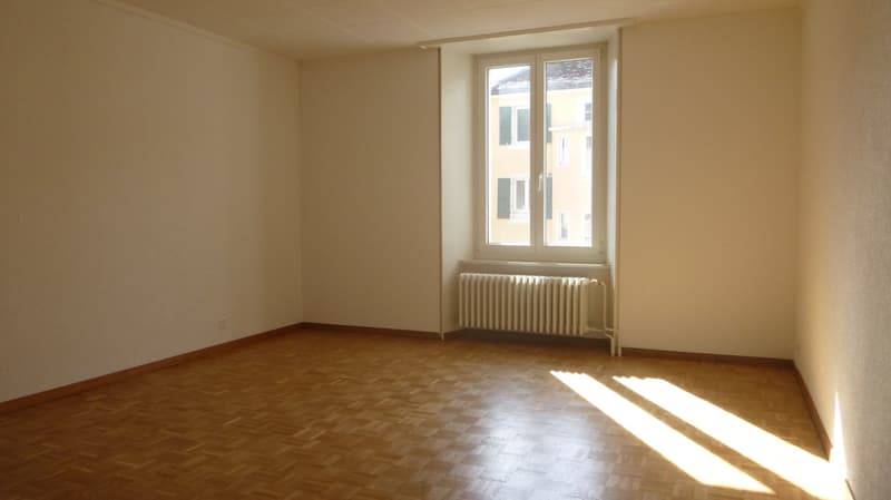 empty room, wooden floor, white walls, window with radiator