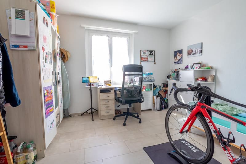 Desk with chair, bicycle, bed, shelves, window, tiled floor