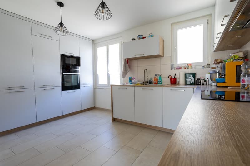 modern kitchen with white cabinets, tiled floor, built-in oven and microwave, sink with faucet, countertop, and various kitchen appliances