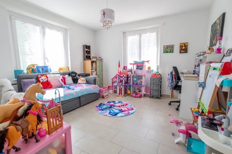 A child's room with a bed, toys, shelves, and a desk.