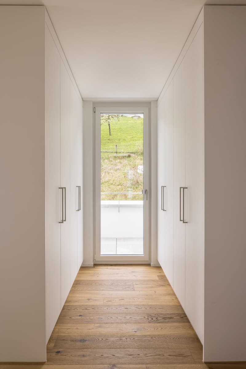 wooden floor, white walls, large glass door, white cabinets, view of the outside
