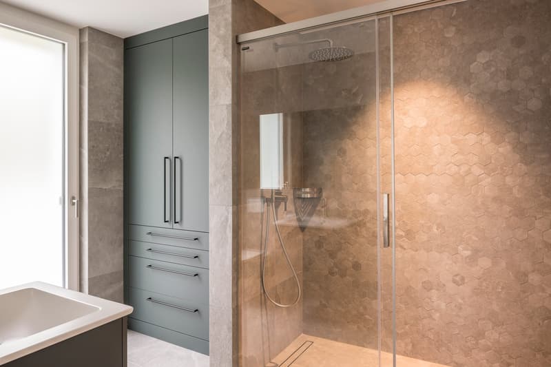 Bathroom with a glass shower, a sink, and a cabinet with drawers.