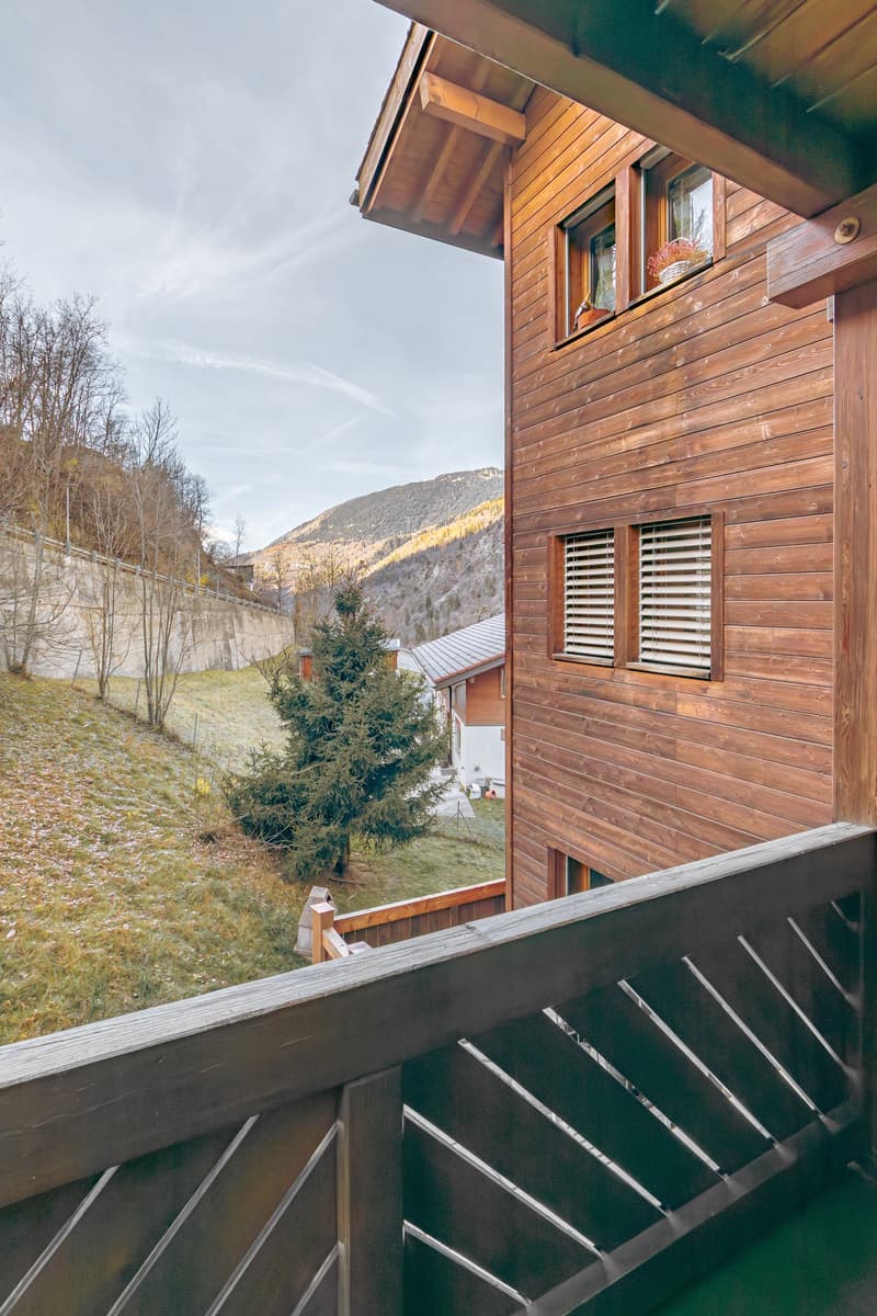 wooden exterior, balcony, green grass, mountain range in the distance
