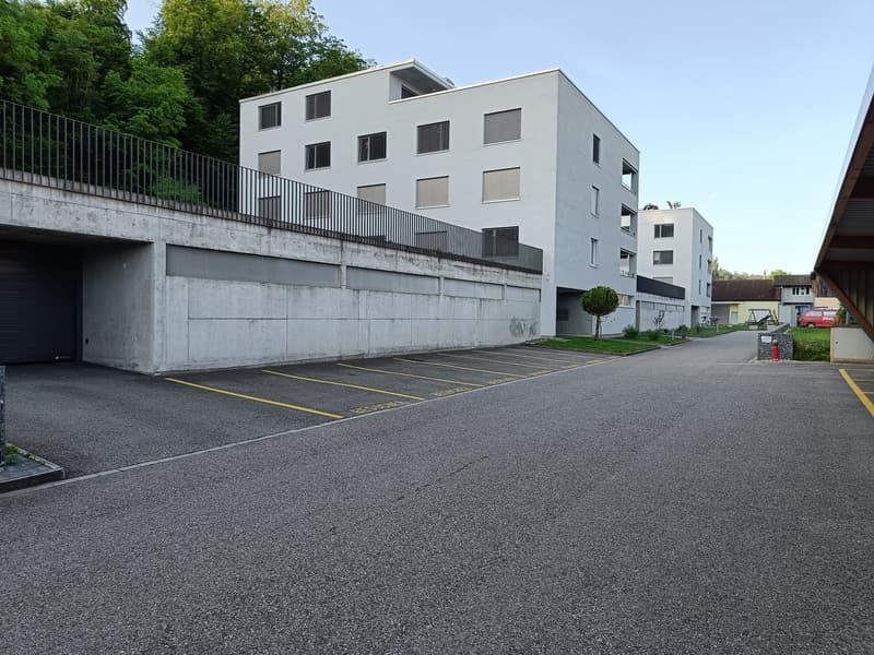 modern apartment building, parking garage, underground parking, metal railing, paved road, fire hydrant