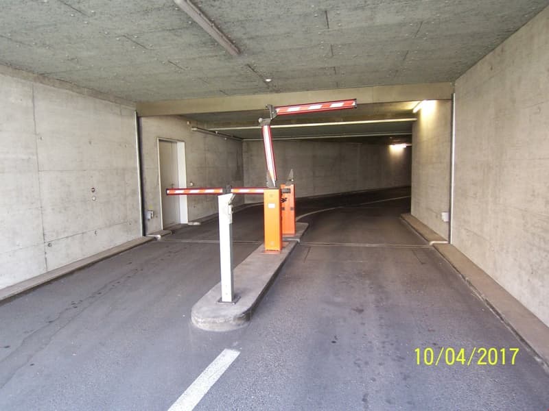 Concrete interior with parking spaces, garage door, and parking equipment