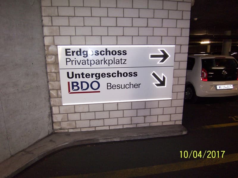 The image shows a sign indicating the directions to the underground parking lot and the BDO visitor entrance.