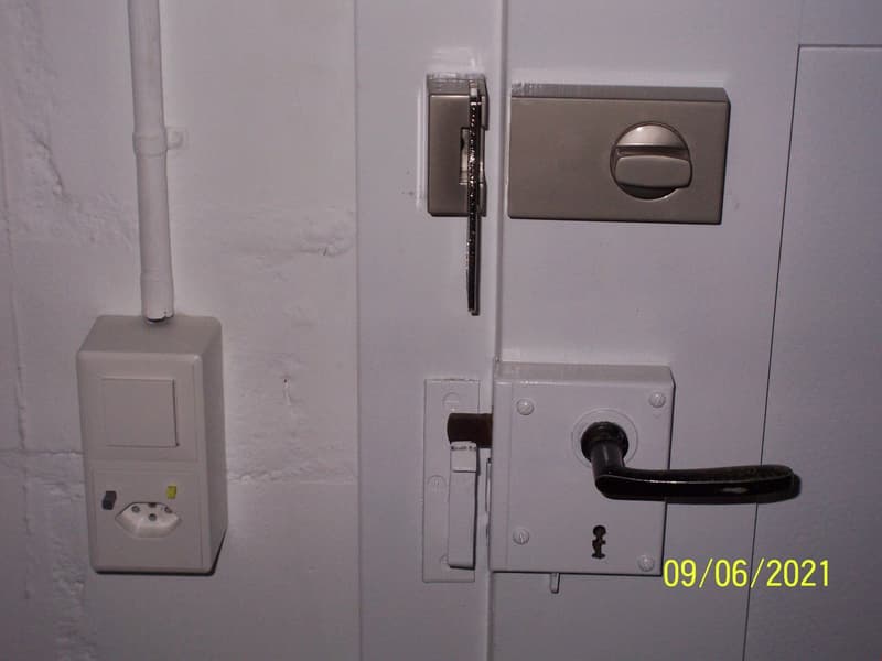 White door with a lock, a switch, and an electrical outlet.