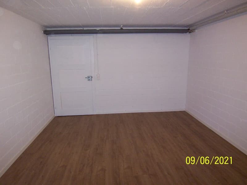 Empty room with white walls, wooden floor, white door, and a power outlet on the wall