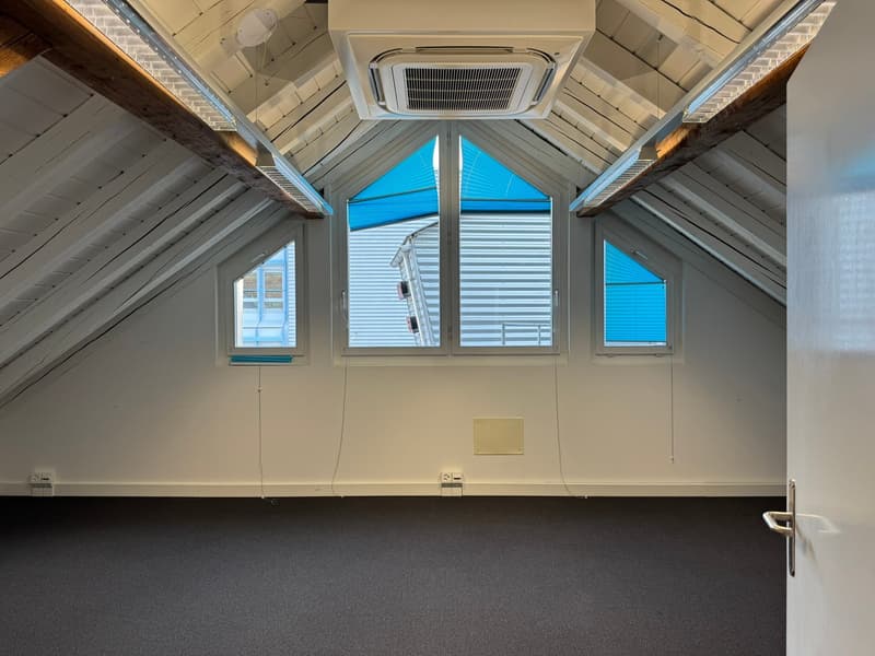 Attic space with vaulted ceiling, large windows, air conditioning unit, and dark carpeted floor
