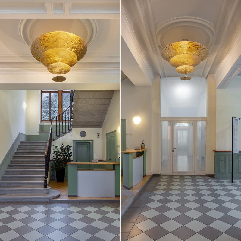 Decorative ceiling lamp, white and grey checkered flooring, staircase, green doors, reception desk, glass doors