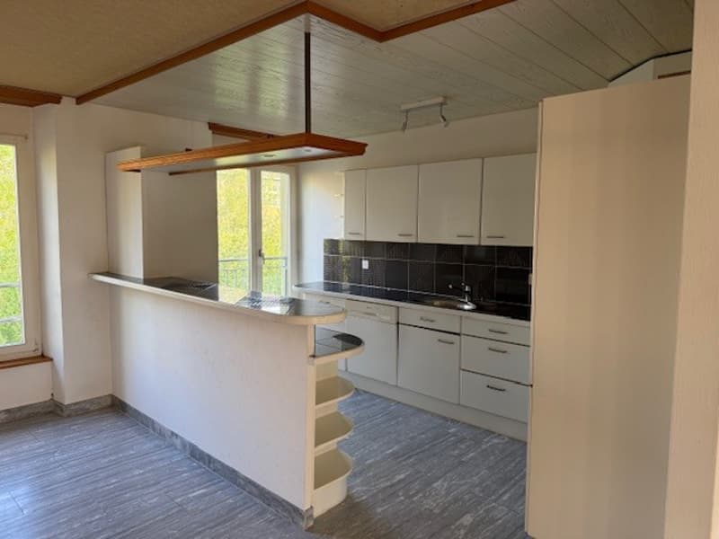 kitchen with island, white cabinets, black tiled backsplash, open balcony