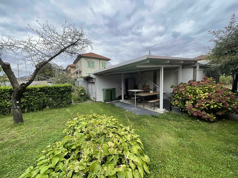 outdoor space with lawn, garden plants, a storage building, table and bench under cover