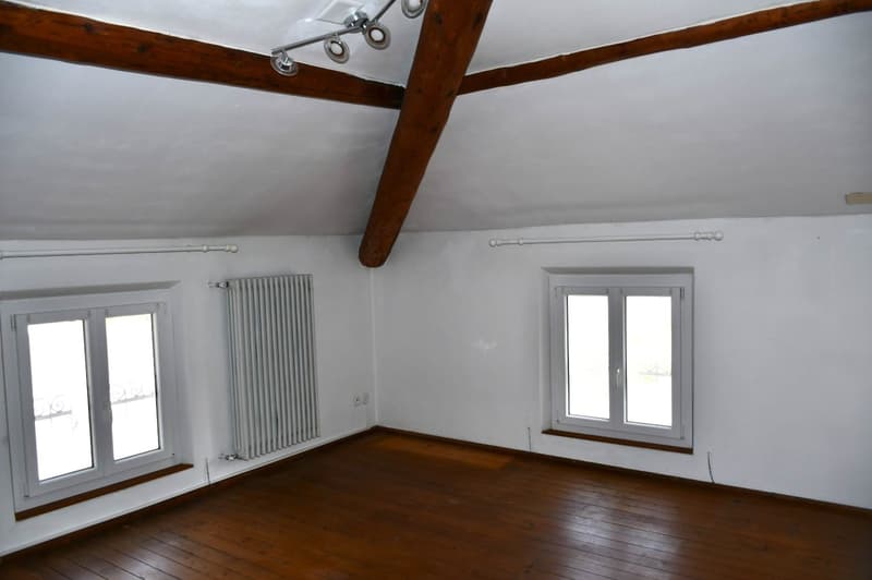 Empty room, wooden floor, white walls, two windows, a heater on the wall.