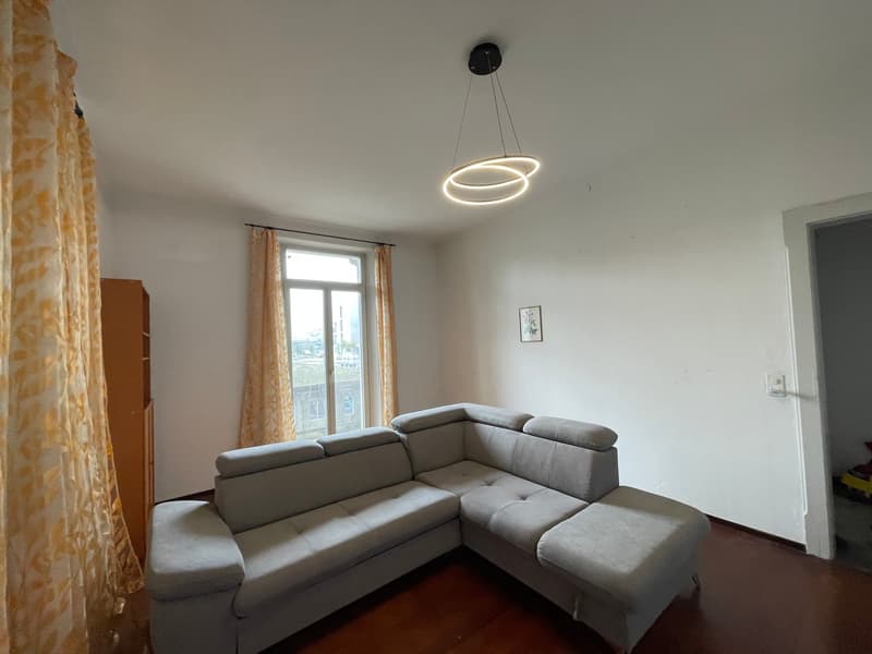 L-shaped grey sofa, large windows, yellow curtains, modern light, wooden floor