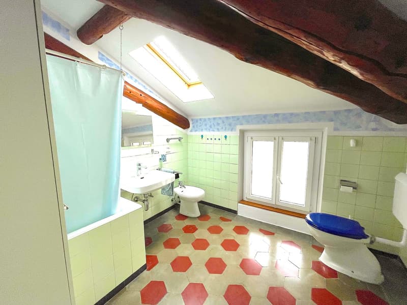 Bathroom with sink, toilet, bathtub, window, wooden beams, hexagonal tiles.