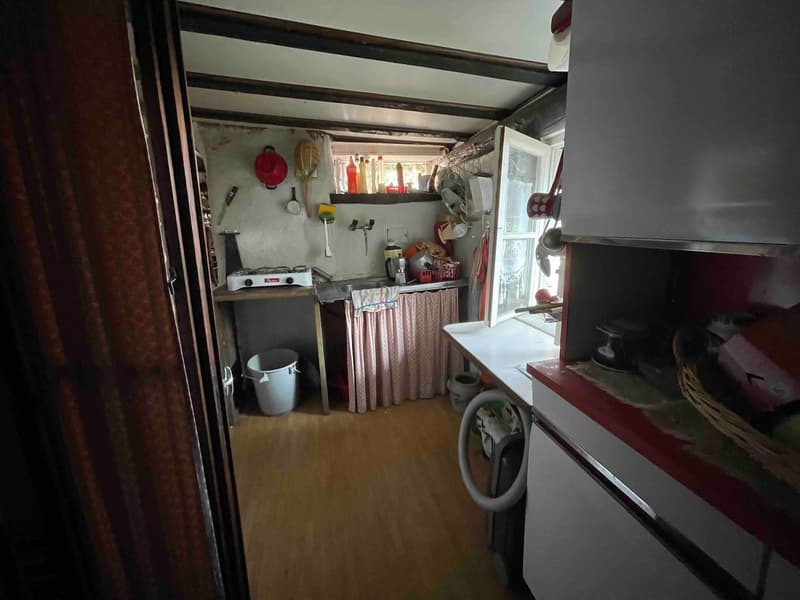 Kitchen with sink, counter, gas stove, washing machine, cabinets, baskets, utensils hanging on the wall