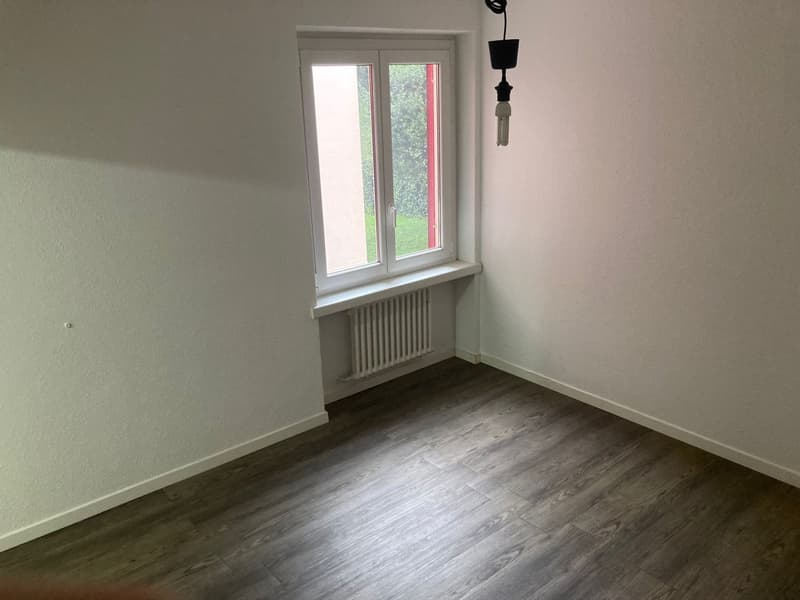 Empty room, white walls, wooden floor, window with radiator