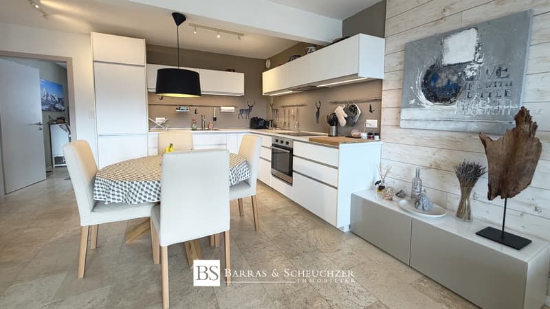 Cuisine / a modern apartment with a kitchen, dining room and living room with a picture on the wall above the table with white chairs