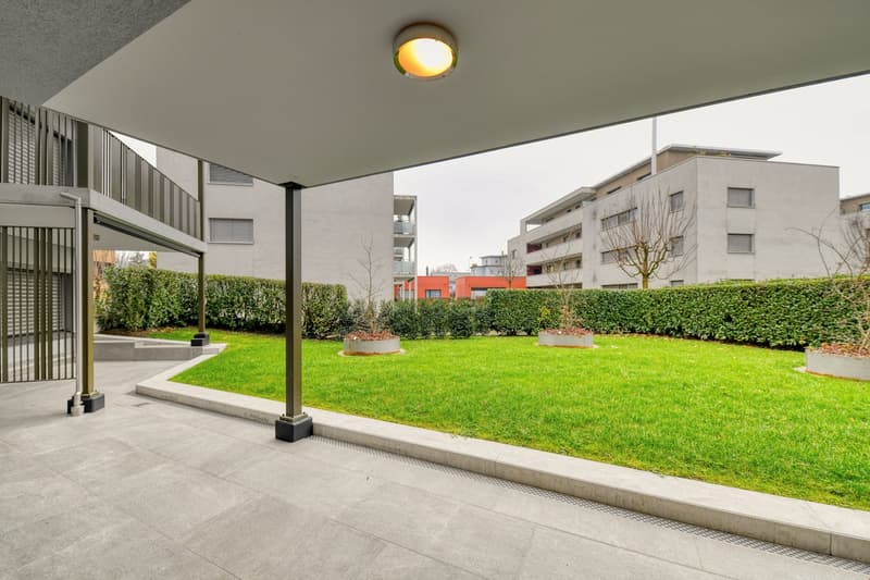 modern apartment garden, paved flooring, metal railing, green grass, cement posts