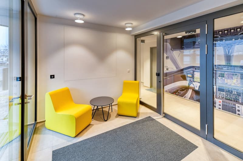modern room with double doors, yellow chairs, grey table, gray rug, white walls, glass walls