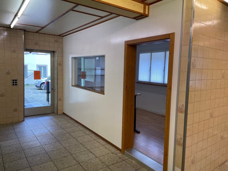 tiles on the floor, white walls, open door to an empty room, glass window, wooden door, hallway with windows